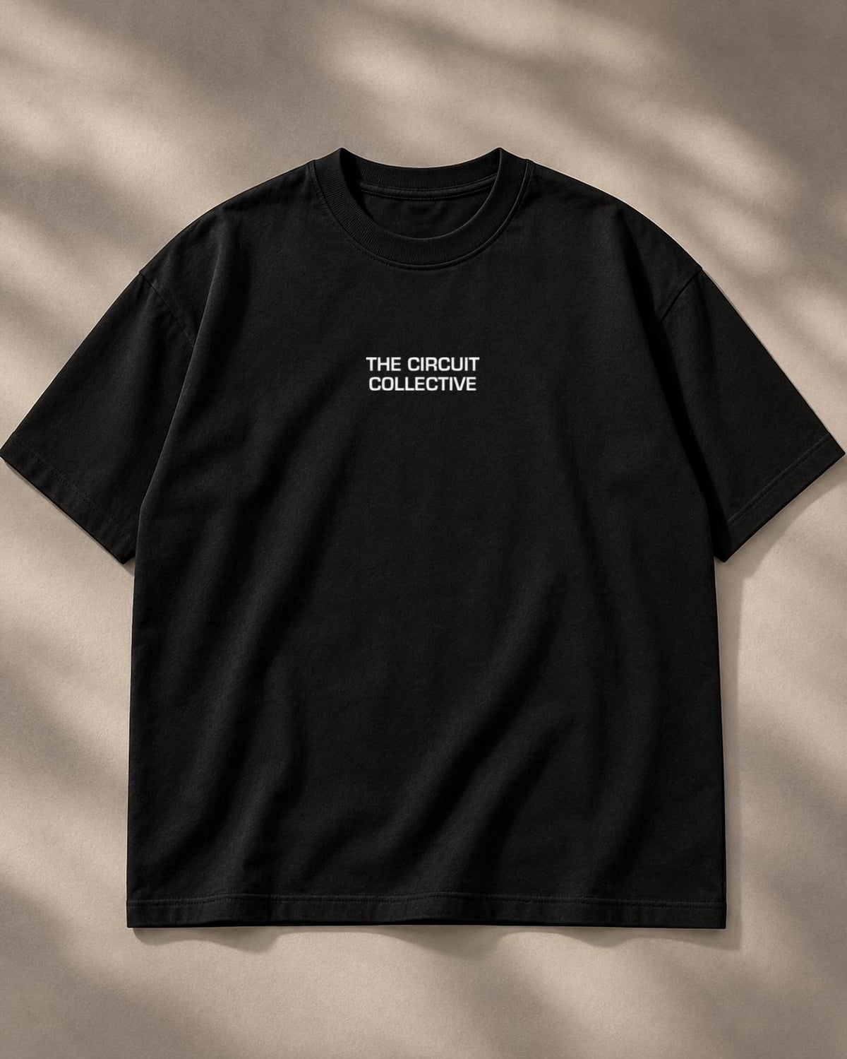 Circuit 001 Detailed tee in black, laid flat from the front: The Circuit Collective wordmark on the chest