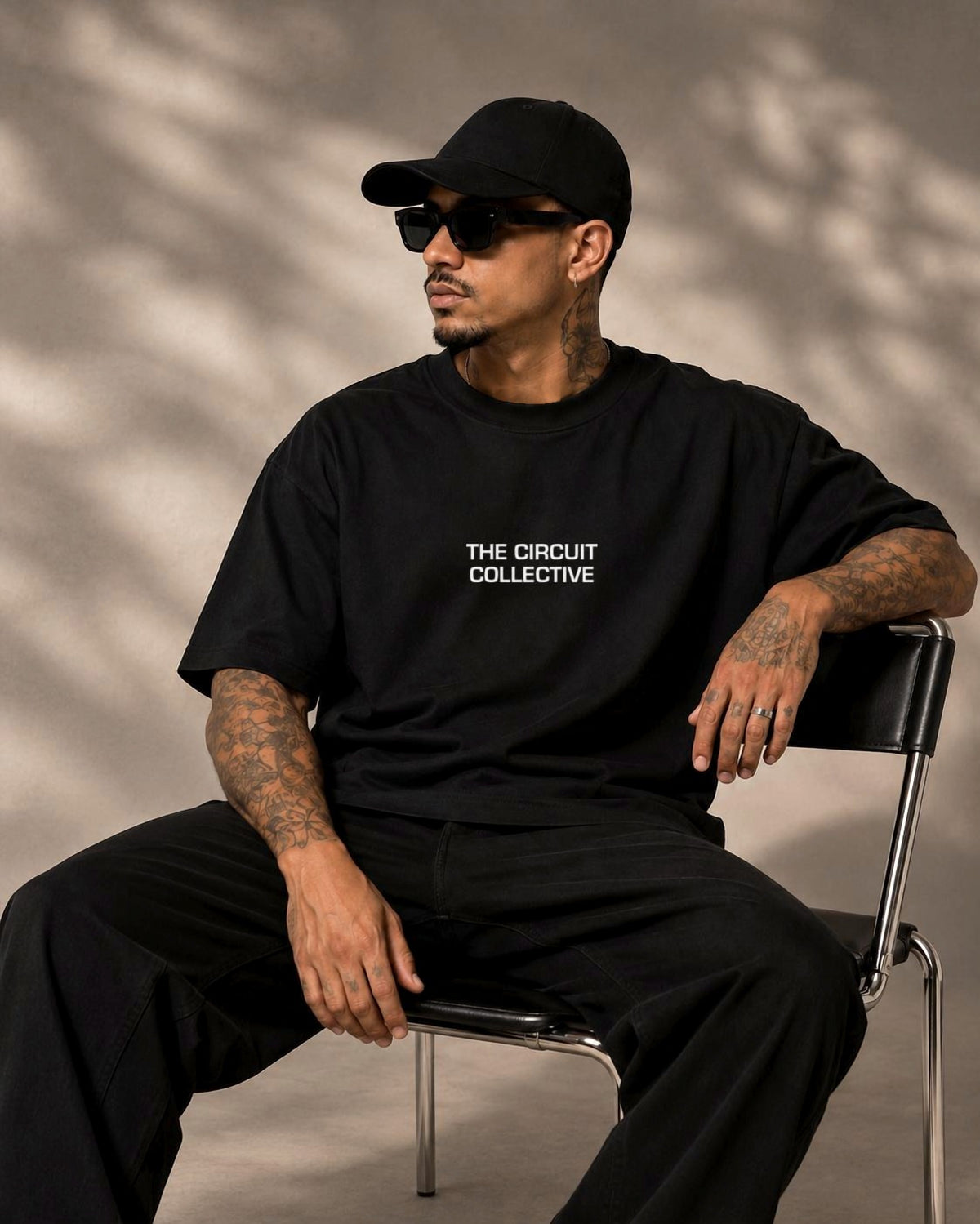 Model seated in the black Circuit 001 Track Only tee, The Circuit Collective wordmark on the chest
