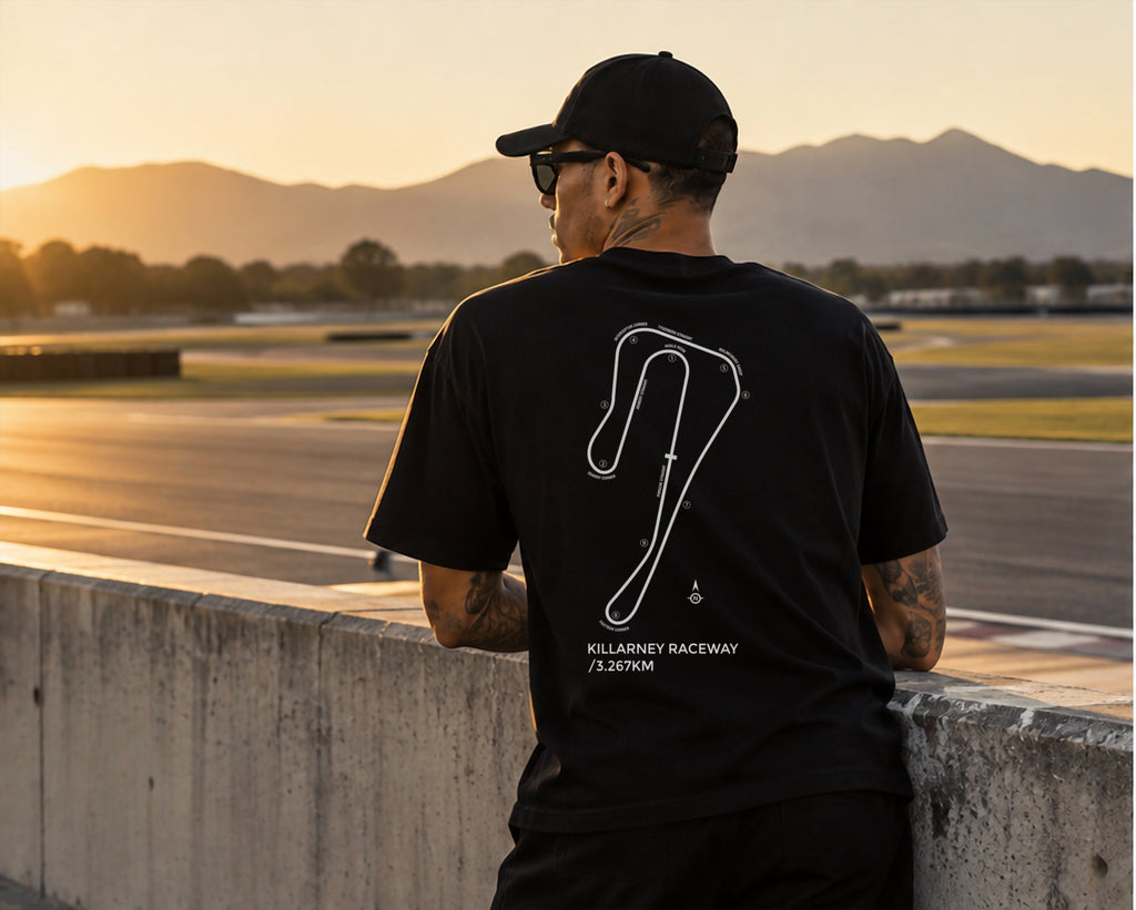 Model at the Killarney pit wall at sunset in the black Circuit 001 Detailed tee, circuit print on the back