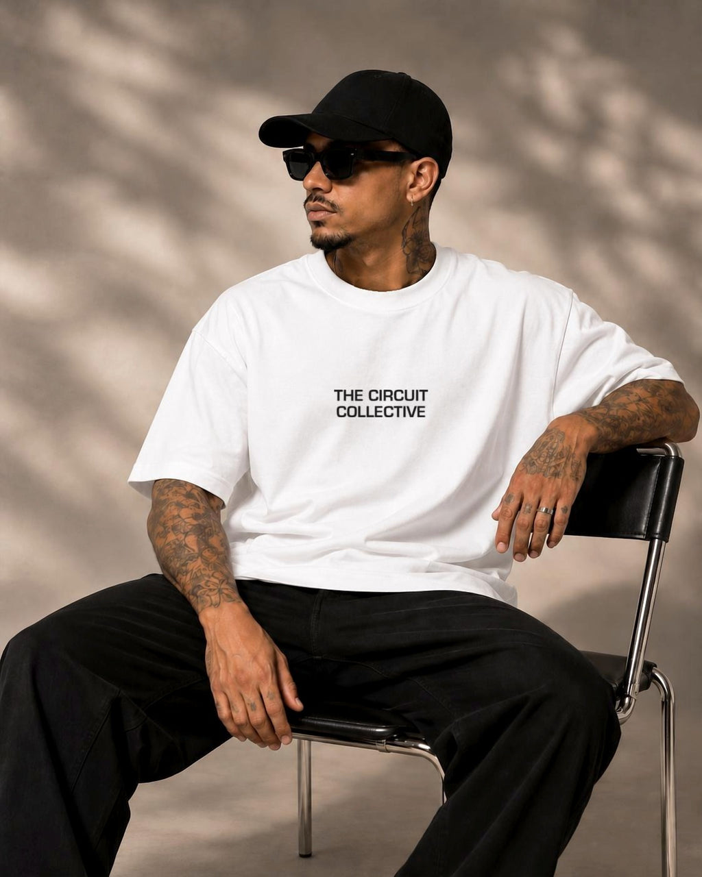 Model seated in the white Circuit 001 Track Only tee, The Circuit Collective wordmark on the chest