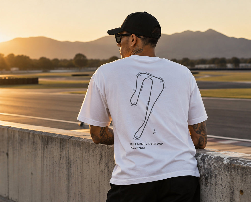 Model at the Killarney pit wall at sunset in the white Circuit 001 Detailed tee, circuit print on the back